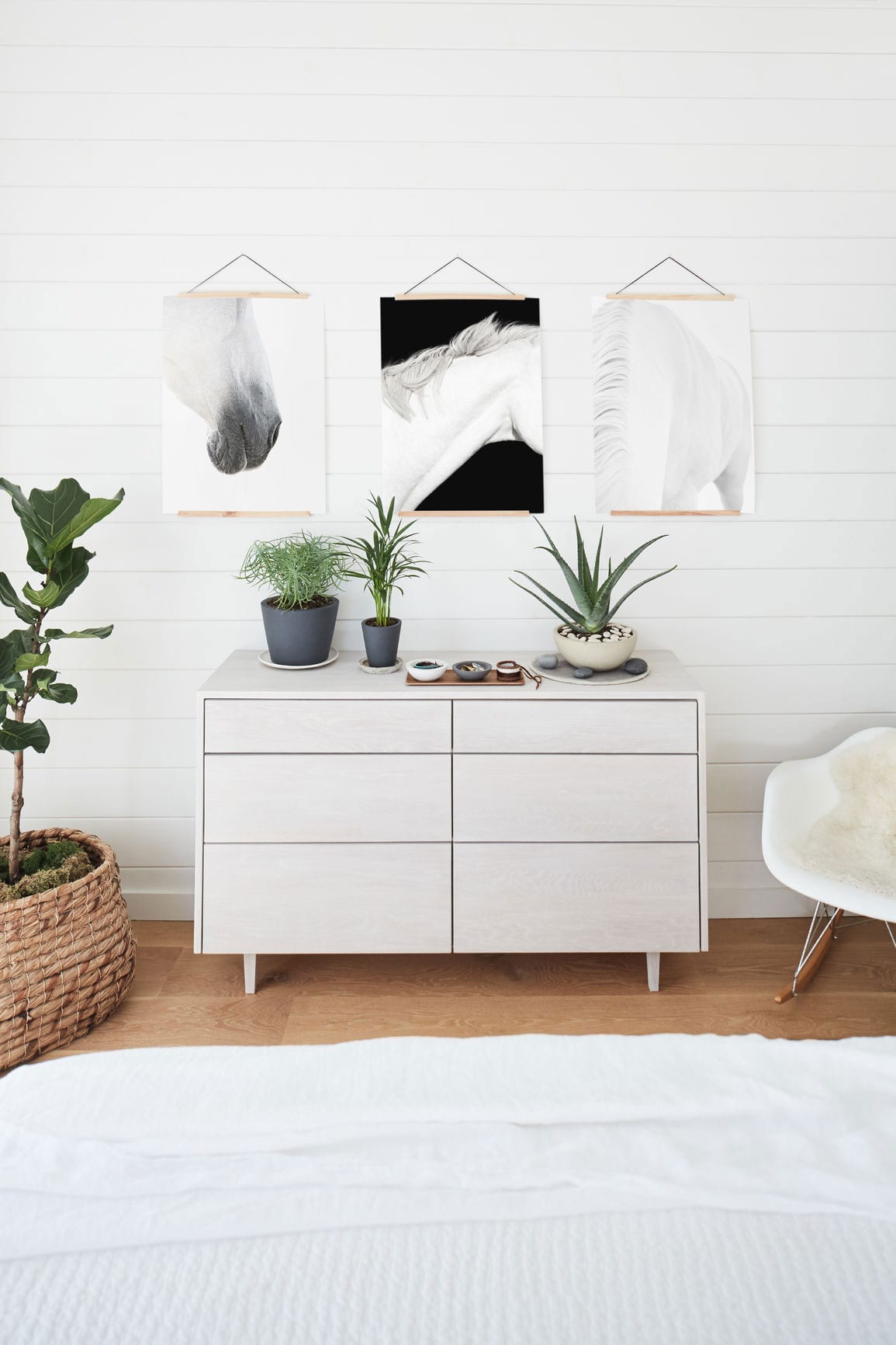 Plants and a jewelry holder on top of a whitewash wood dresser.