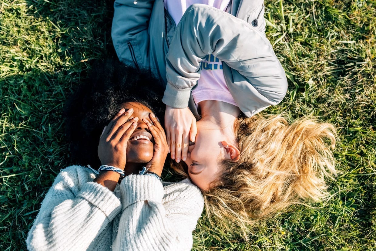 Two best friends telling secrets lying in the grass.