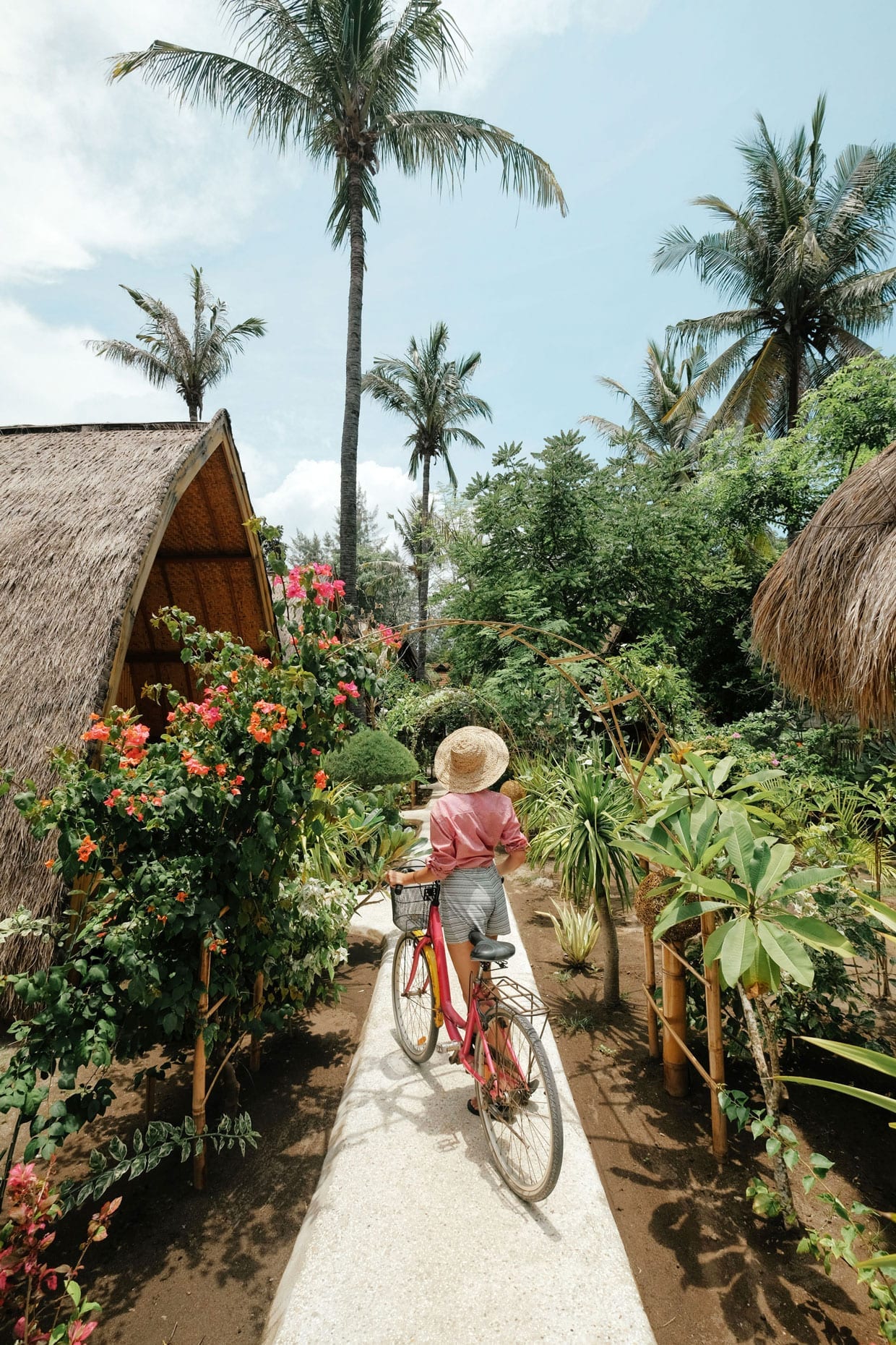A woman with a bike in a tropical location.