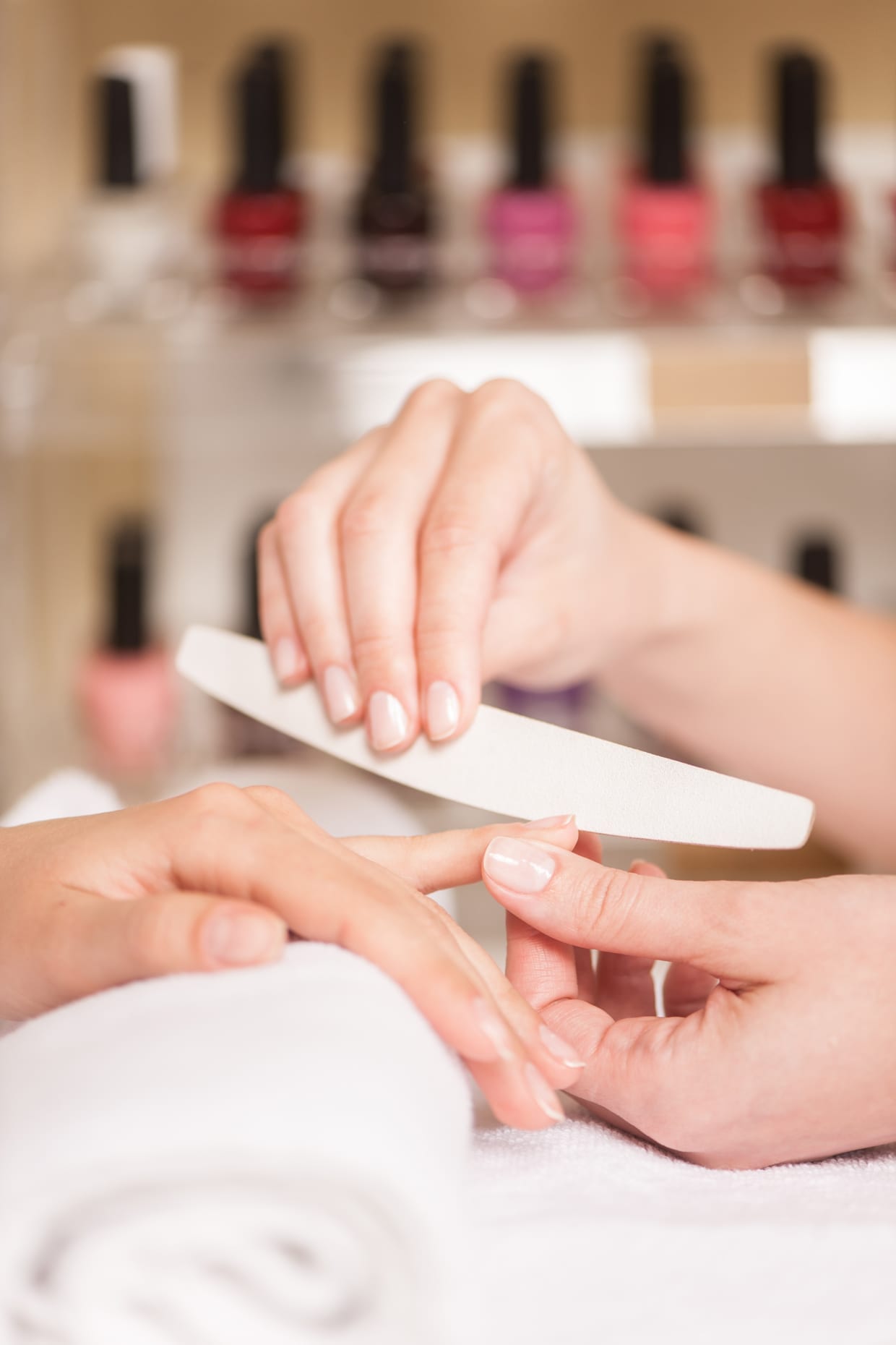 Close-up of beautician hand filing a woman's nails in a salon.