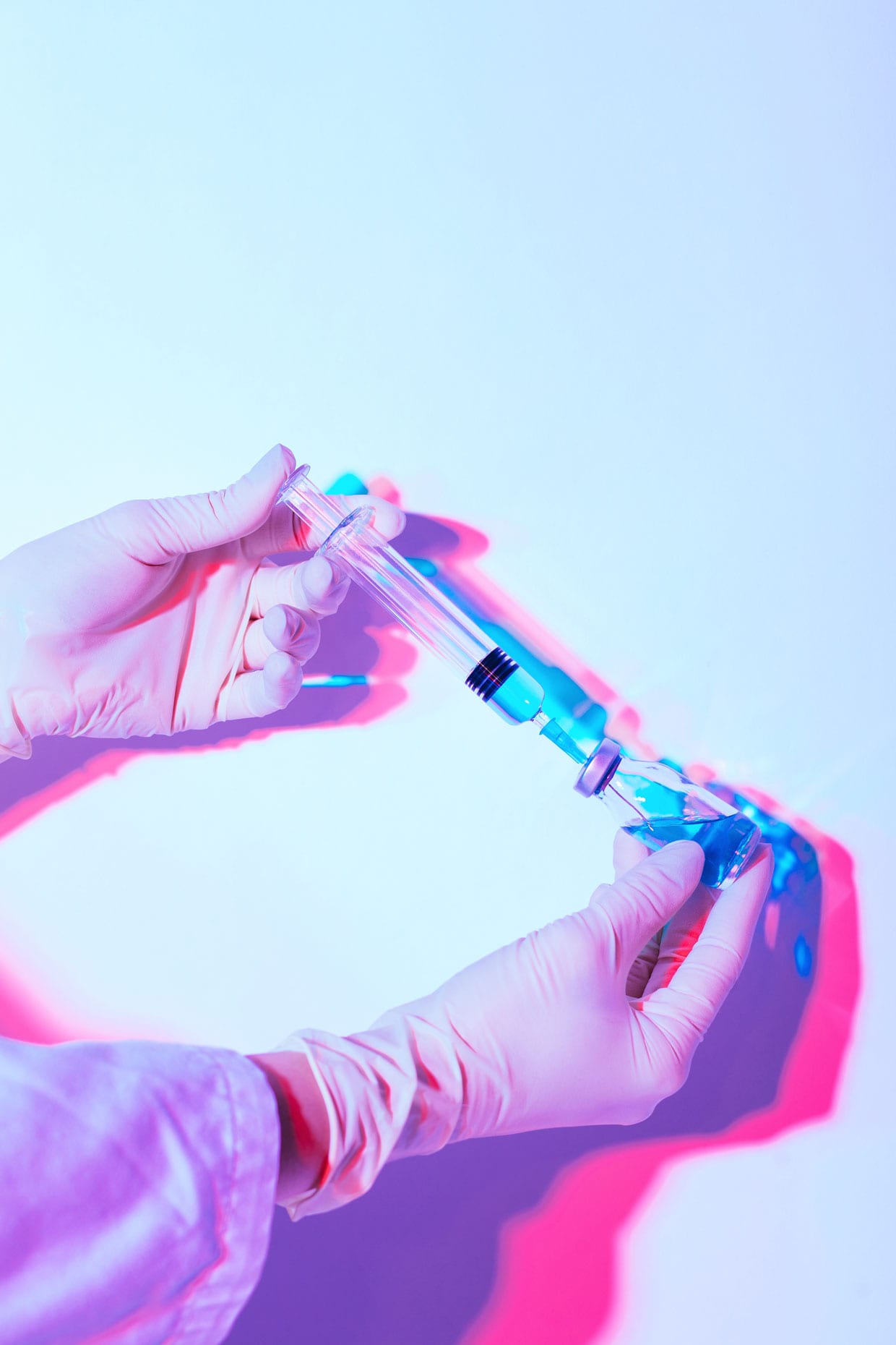 A photo of hands holding a syringe and vial.