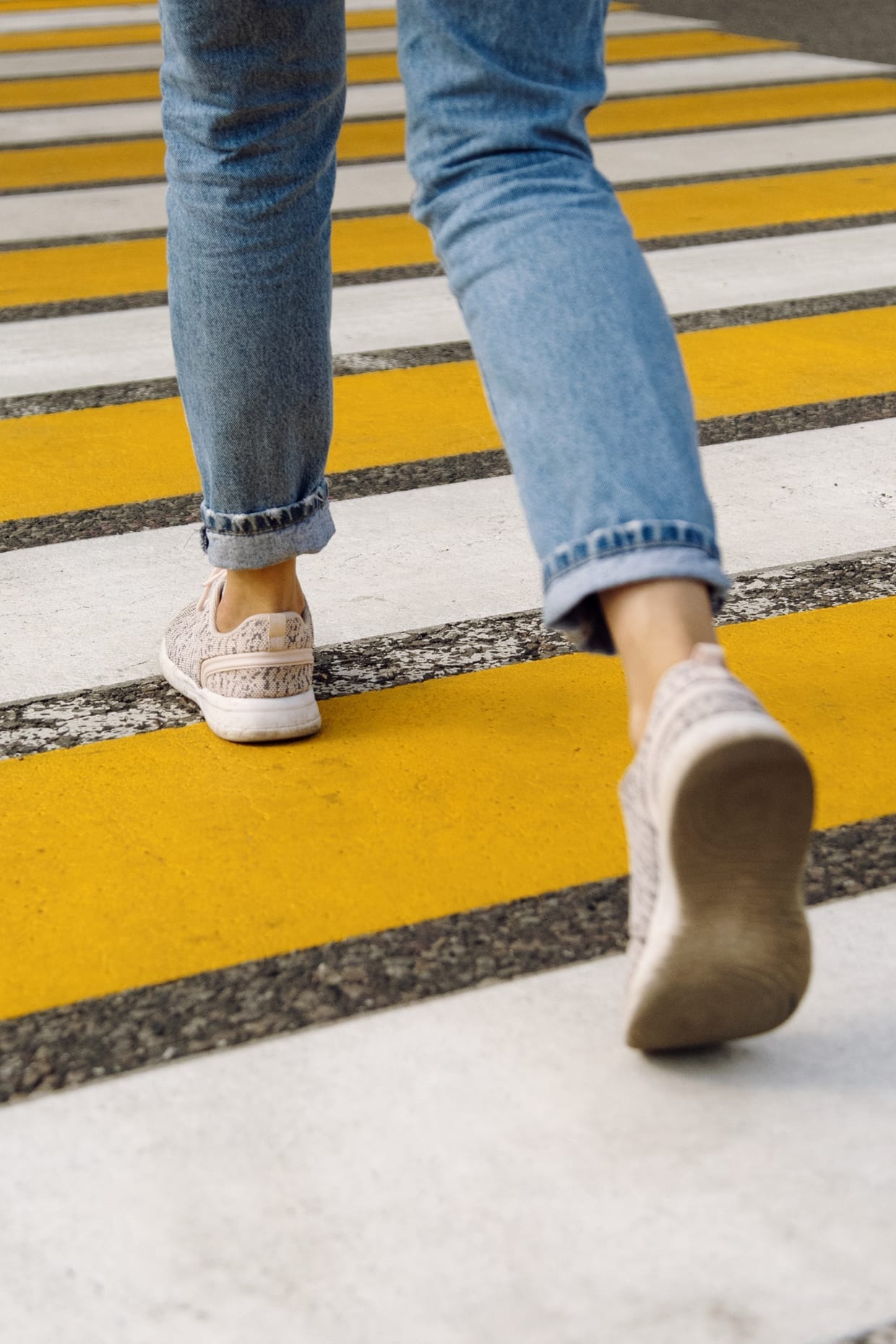 Camera zoomed towards woman's leg across crosswalk.