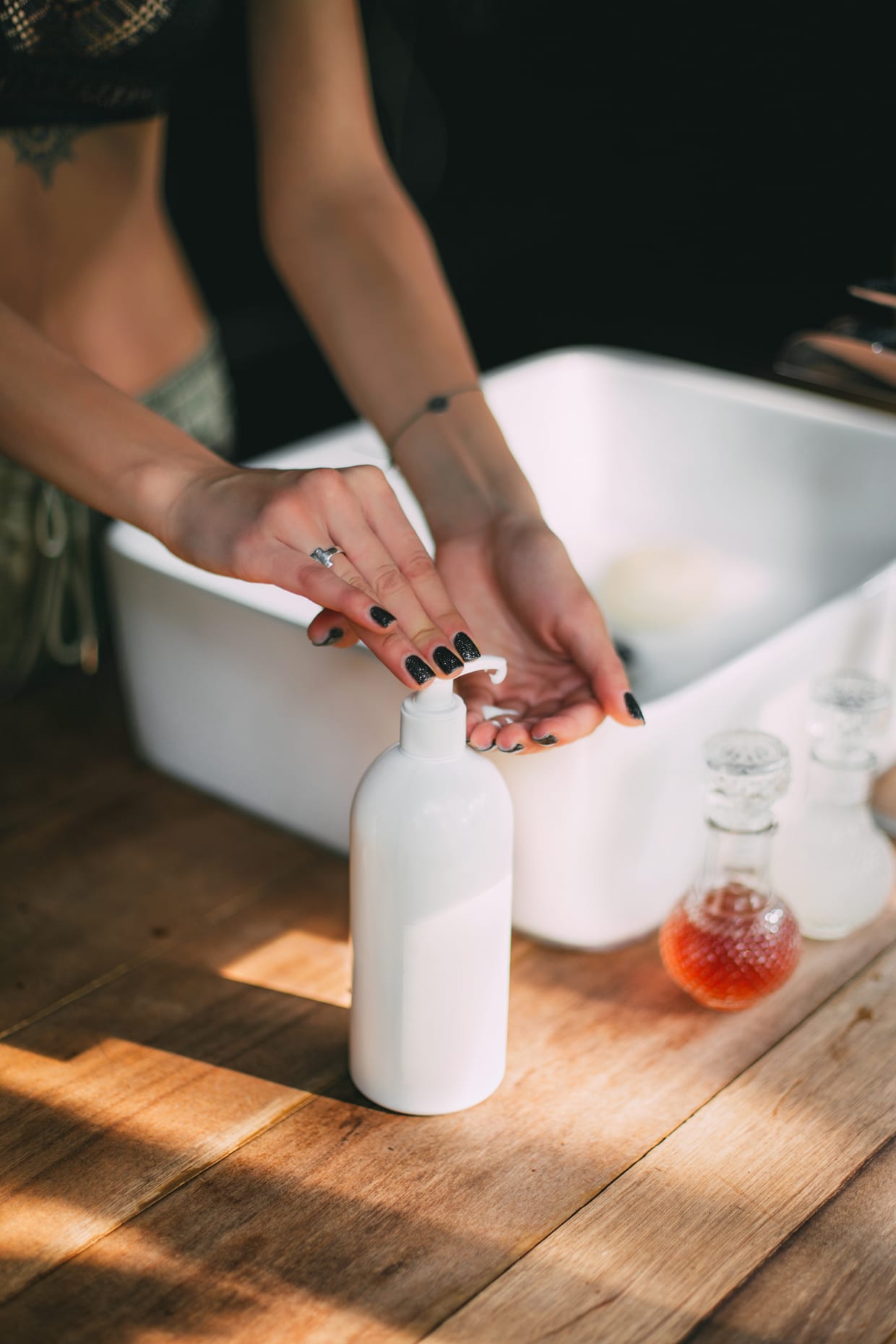 A woman's hands on a bottle of hand soap.