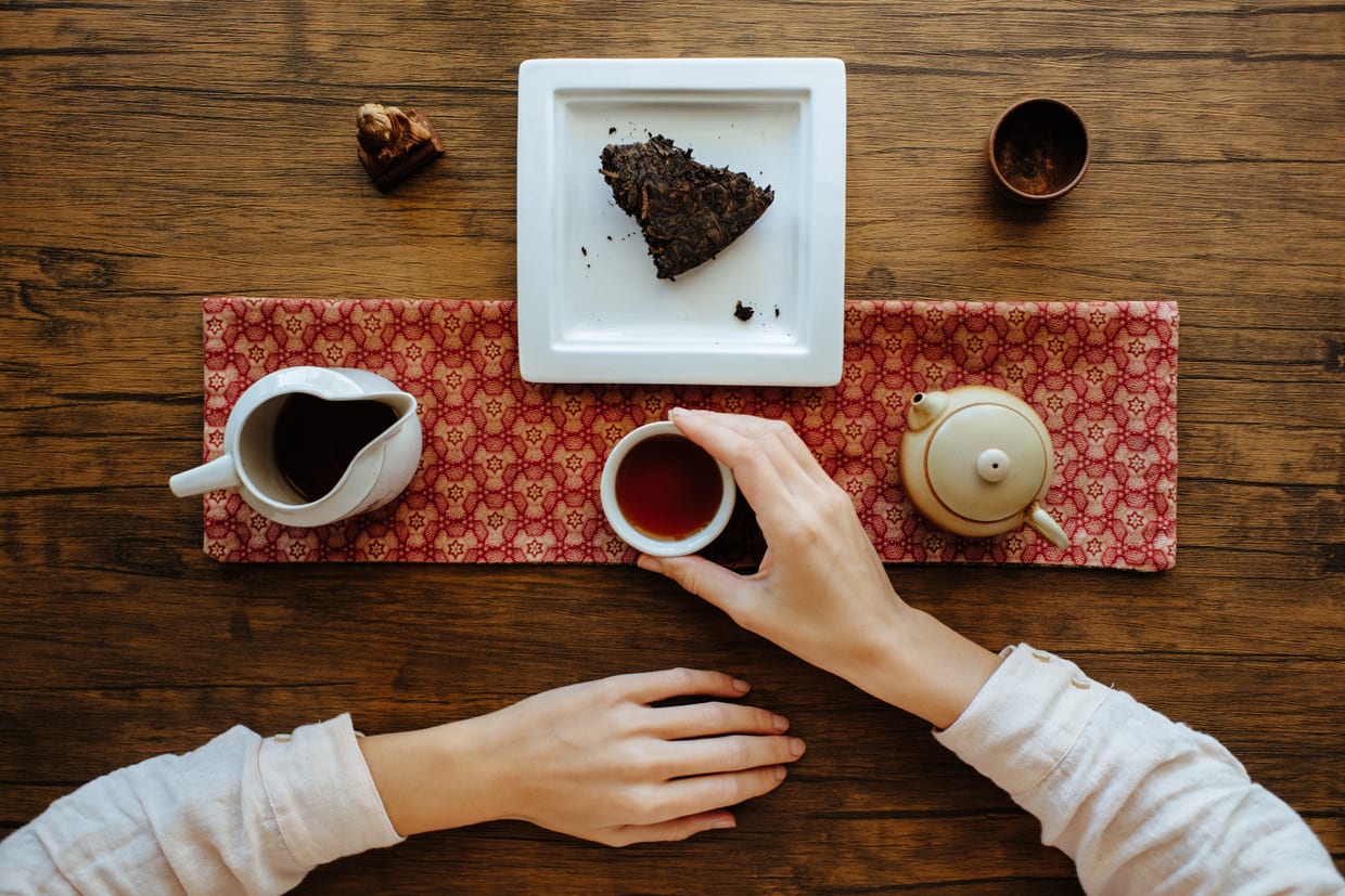 An overhead shot of a woman drinking pu-erh black tea.